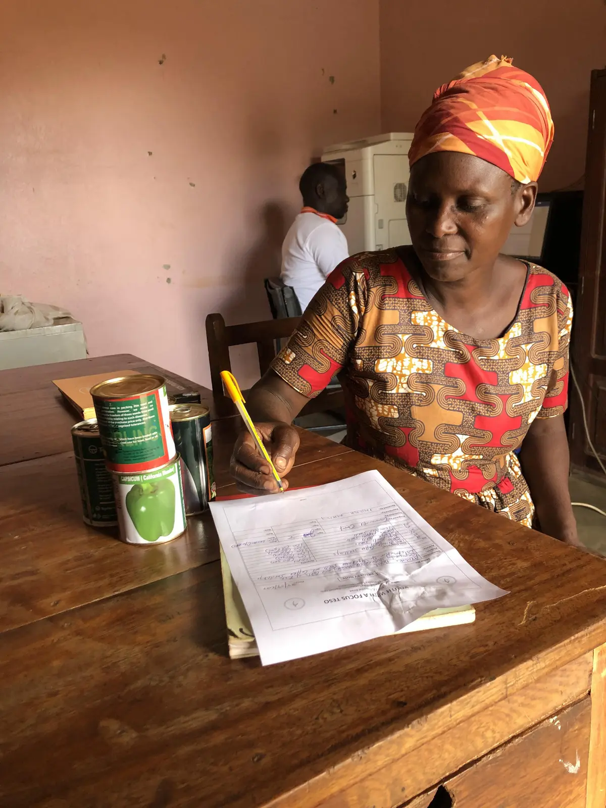 A woman completes programme documentation alongside agricultural inputs